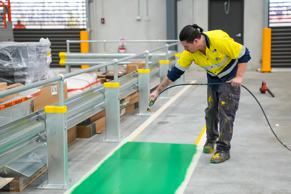 Barrier Group technician applying a green pedestrian walkway inside an industrial facility